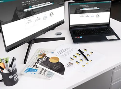 Portátil y monitor sobre la mesa, junto a un portalápices y unos documentos.