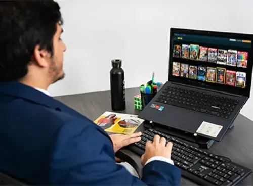 Persona frente a un portátil, con un termo y un libro a un lado.